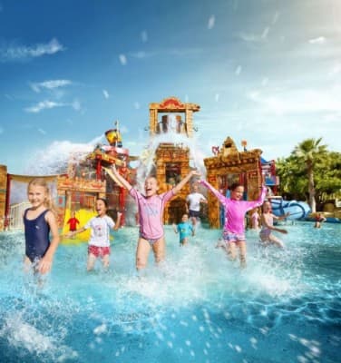 Kids playing joyfully in the water at Dolphin Kayak Dubai water park, surrounded by colorful slides and splashes.