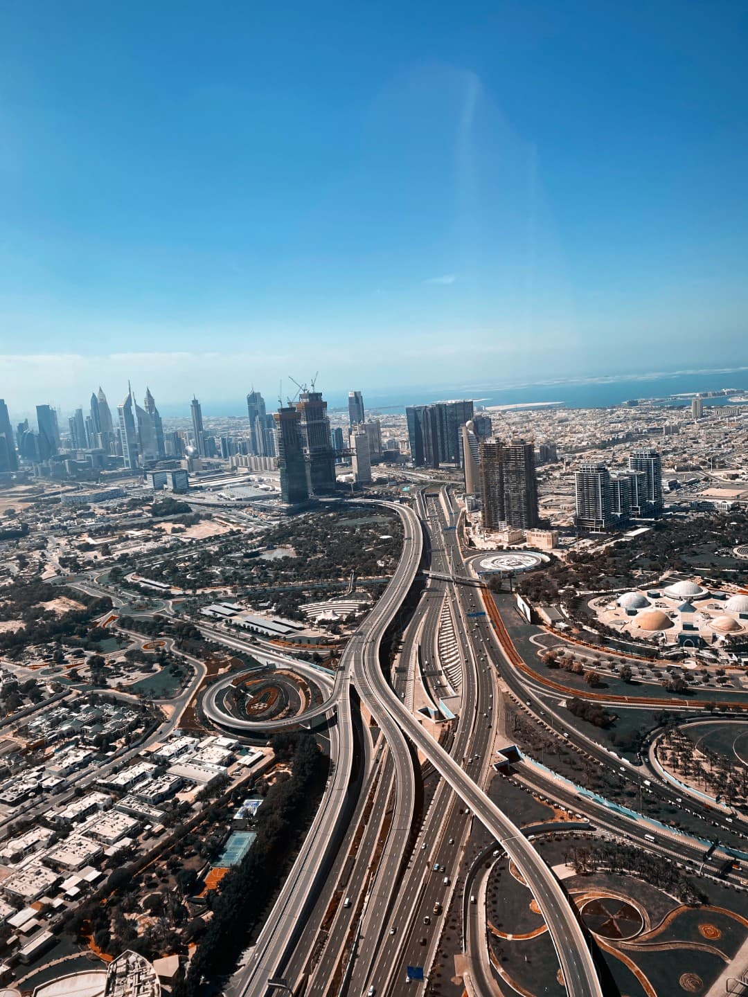 Aerial view of a sprawling cityscape with intersecting highways, surrounded by modern skyscrapers