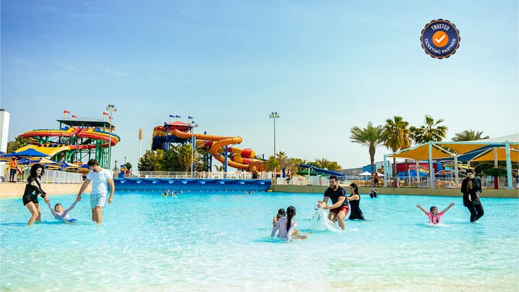A vibrant water park scene featuring large, twisting orange and yellow slides.