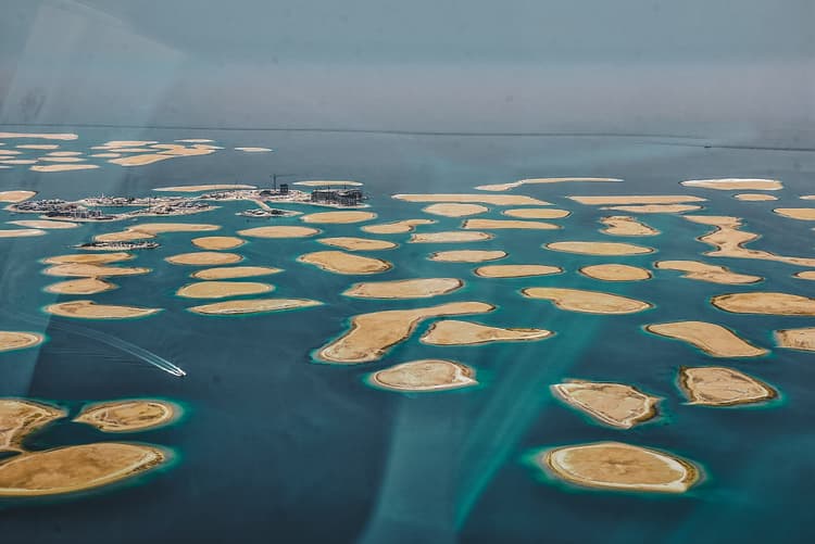 Aerial view of an archipelago showing numerous small, sandy islands surrounded by turquoise water, with a distant boat.