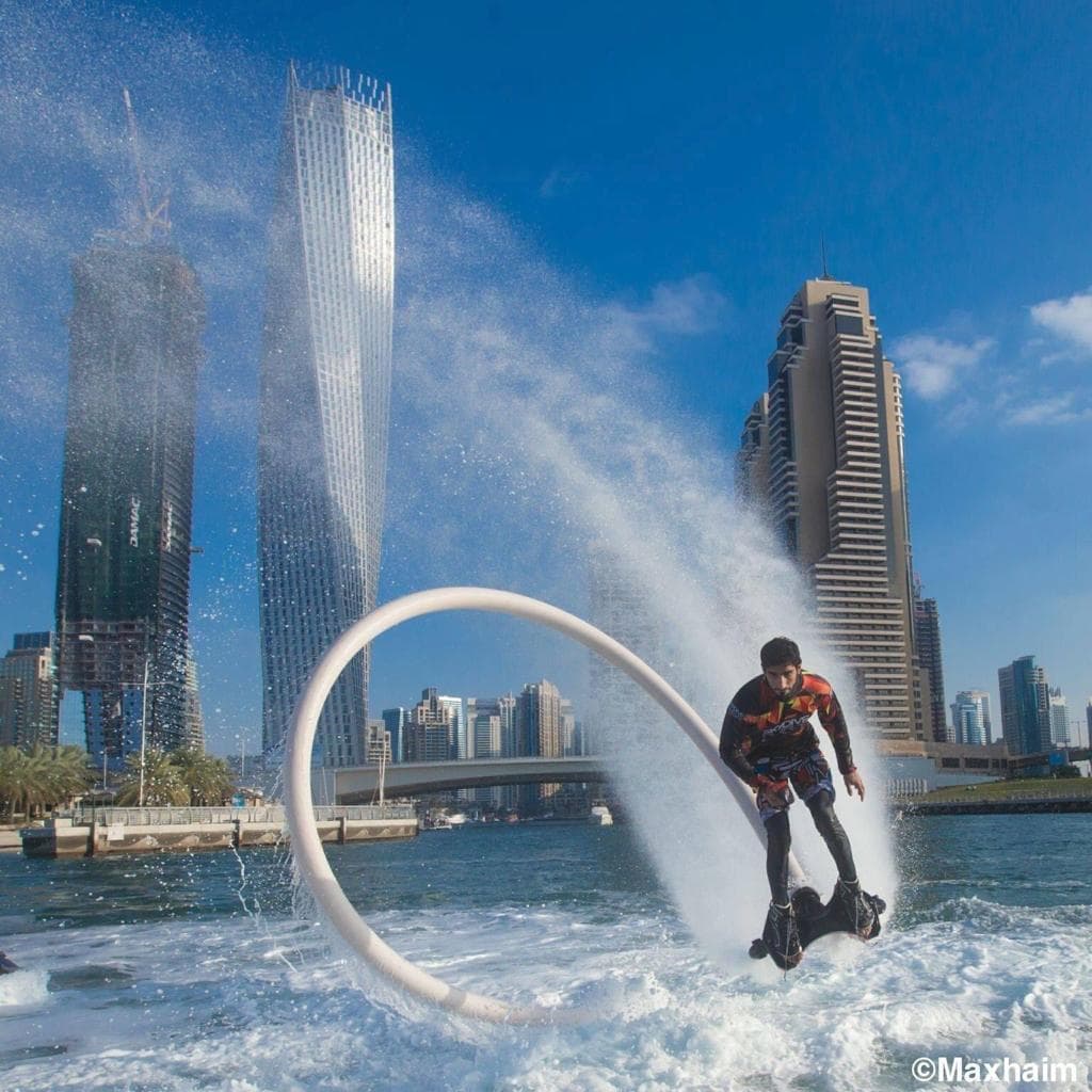 A man water skiing with a large hose, showcasing the Flyboard Dubai Solo experience on the water.