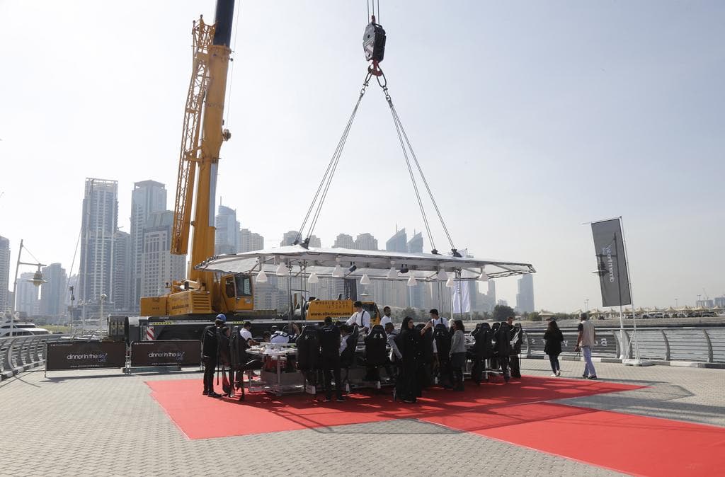 A group of people standing on a red carpet at the Dinner In The Sky event