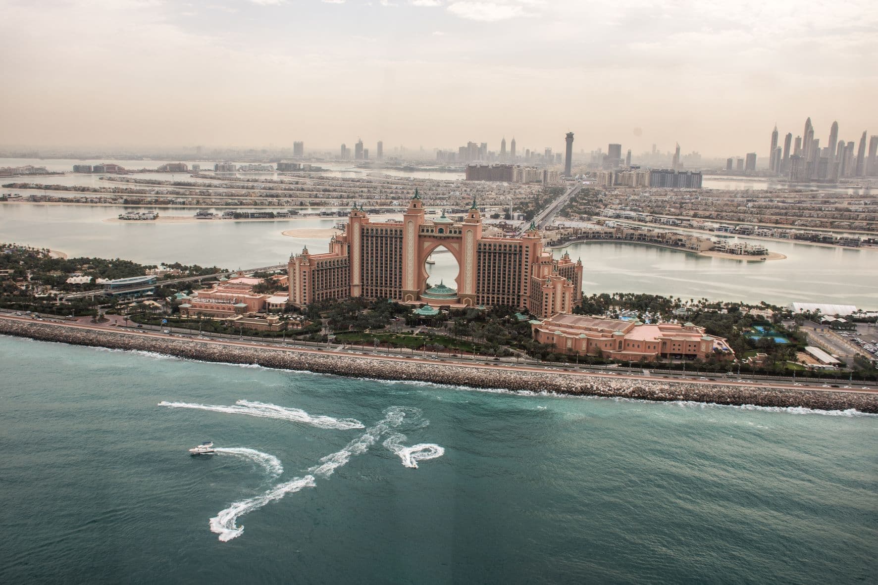 Aerial view of Atlantis The Palm hotel in Dubai, with grand arches and towers, surrounded by blue water