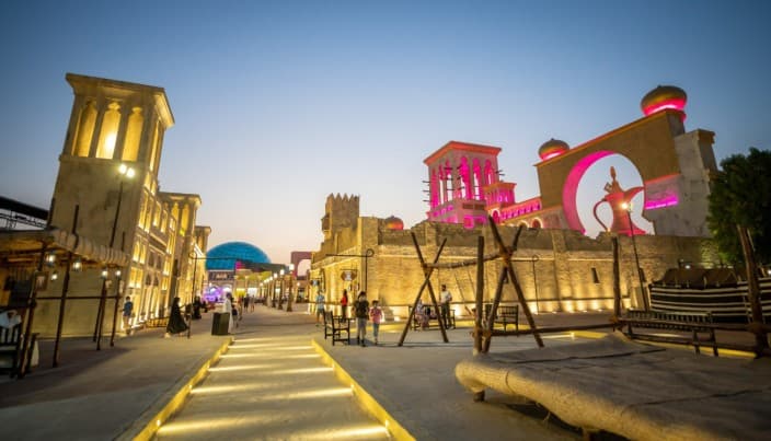 Bustling evening scene at a vibrant cultural village, featuring illuminated traditional architecture