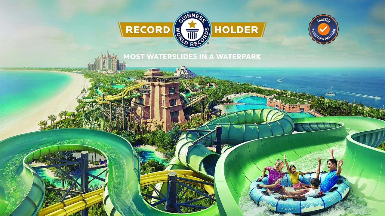 Tropical waterpark with twisting green slides, palm trees, and a beach. Four people cheer on a blue raft. Text: "Most Waterslides in a Waterpark
