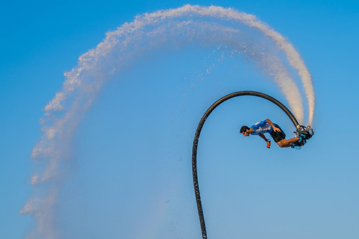 A man performs a trick on a water jet during a Flyboard activity at Dubai Marina.